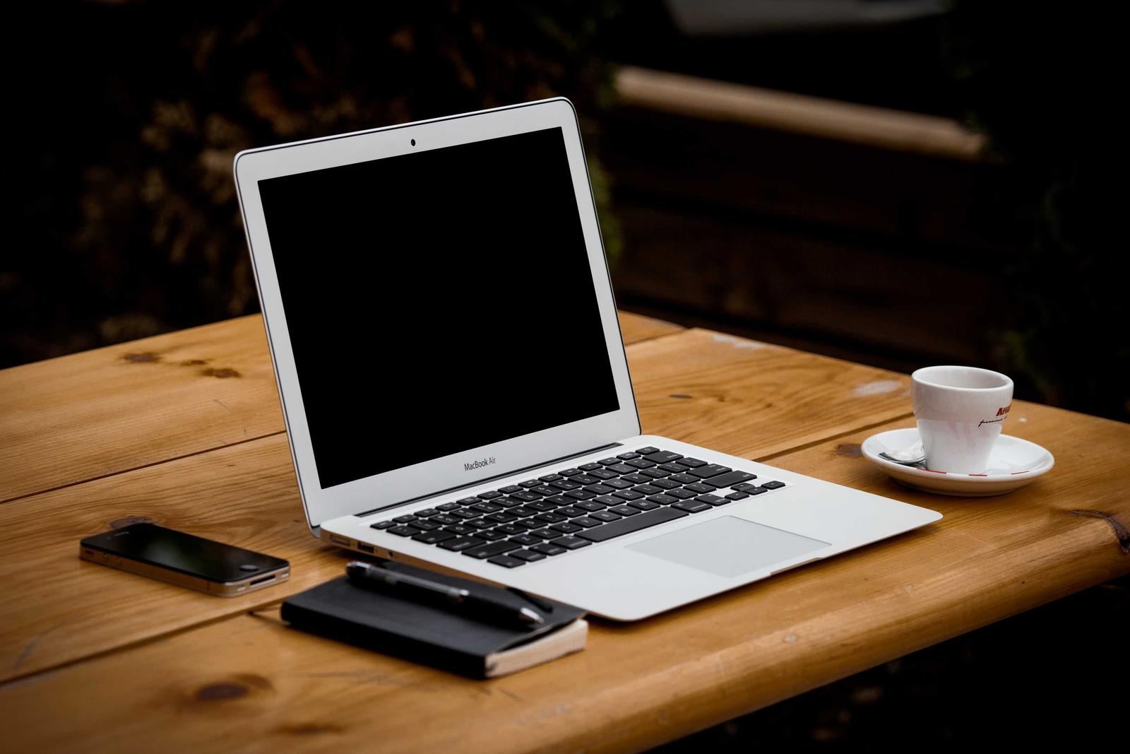 A laptop, phone and coffee on a wooden desk