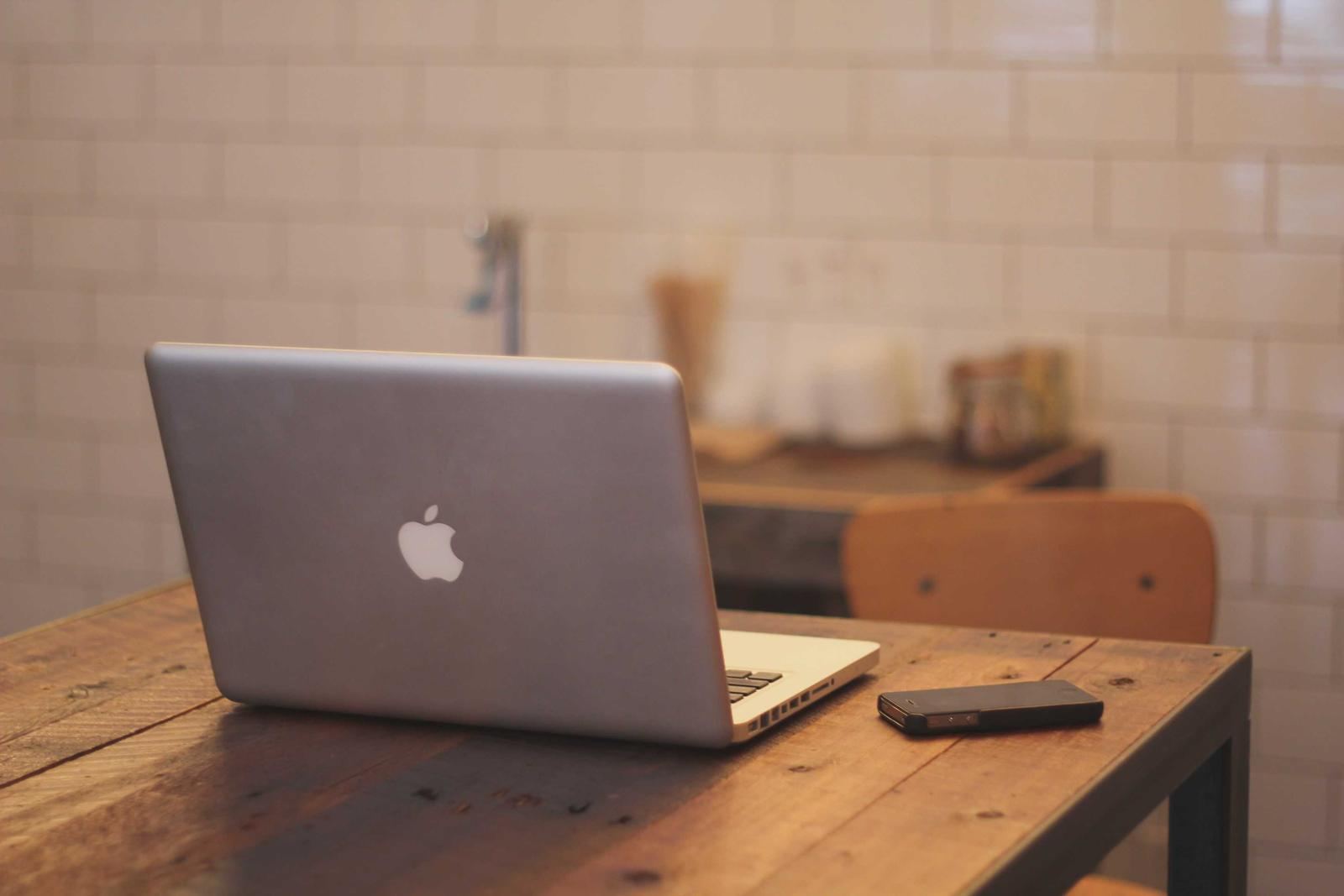A laptop on a wooden table in a bright room