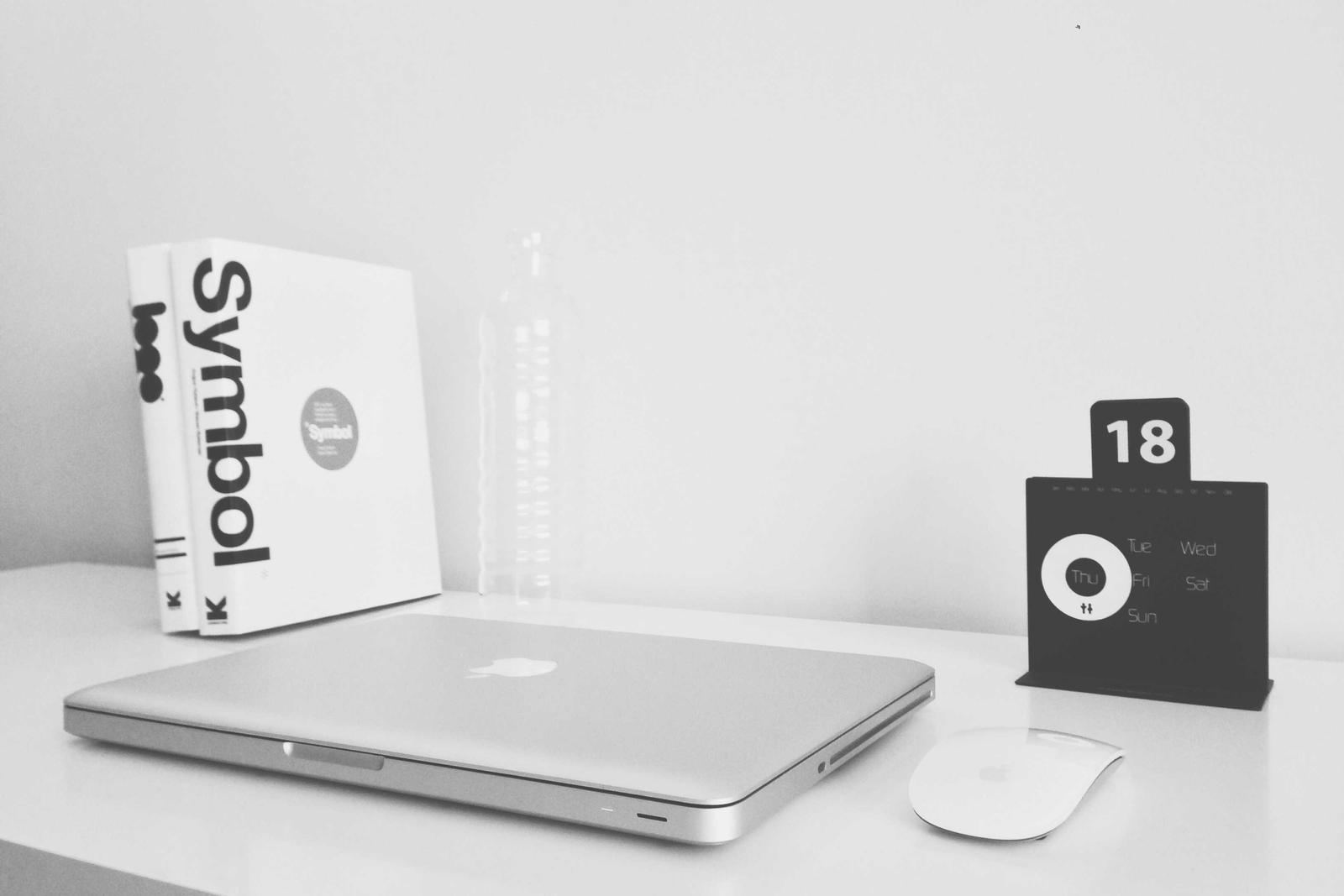 A closed laptop beside books on a bright desk