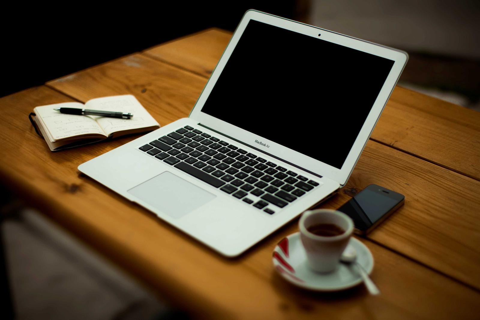A laptop, notebook and phone on a work table